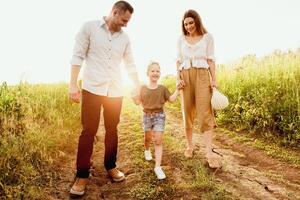 Concept Of A Happy Family. Cheerful parents walking with their kid and holding her by hands photo