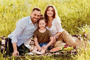 Happy Moments. Portrait of loving family enjoying picnic on a sunny day, sitting on grass and posing at camera photo