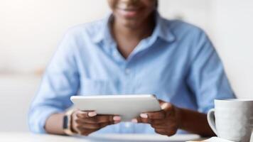 Unrecognizable Black Female Using Digital Tablet While Sitting At Workplace In Office, Enjoying Modern Technologies For Business, Cropped Image With Selective Focus On Device In Hands, Free Space photo