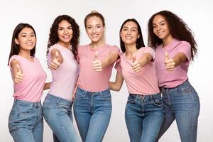 Group Of Smiling Multiracial Ladies Gesturing Thumbs Up Liking And Recommending Something Standing Posing Over White Studio Background. We Like And Approving It, Thumbs-Up Gesture Concept photo
