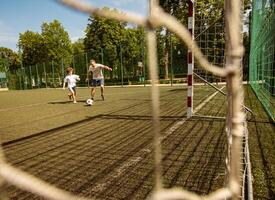 Soccer Match. Two men playing football on the pitch, following the ball, trying to score a goal, view through the net photo