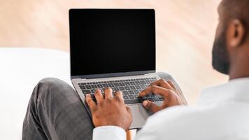 Unrecognizable African American Man Using Laptop With Black Blank Screen, Over Shoulder View, Mockup Image With Copy Space photo