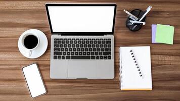Office Workplace. Flat lay of laptop and cell phone with white monitors for mock up, notebook and coffee on the table photo