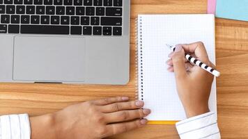 Workspace. Unrecognizable businesswoman working at laptop and writing in notebook in modern office, top view, copy space photo