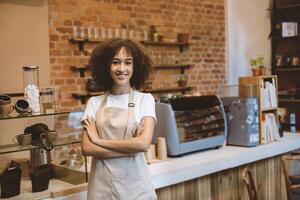 Opening small business and return to normal after covid-19 pandemic. Happy african american lady in apron near bar counter and looking at camera, waiting for clients in modern loft cafe, empty space photo