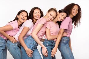Five Cheerful Multiethnic Women Hugging Smiling To Camera Posing Standing Over White Studio Background. Friends Relationship, Multicultural Female Friendship And Unity Concept photo