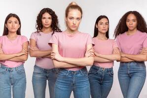 Displeased Mixed Women Standing Crossing Hands Disapproving Something Posing Looking At Camera With Serious Expression Over White Studio Background. We Don't Accept It Concept photo