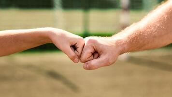 Support Concept. Man giving fist bump to kid in nature background, power of teamwork, selective focus photo