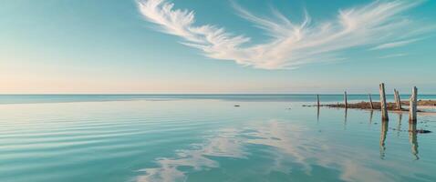Calm turquoise waters reflect a clear sky during midday in a serene coastal location. photo