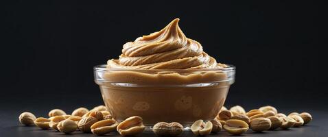 Peanut butter ice cream in a glass jar with peanuts on a black background photo