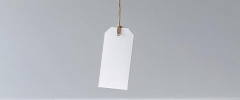 Blank white paper tag hanging from string on white background photo