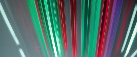 Glowing vertical bars in shades of green and red with reflections on a shiny surface below them photo