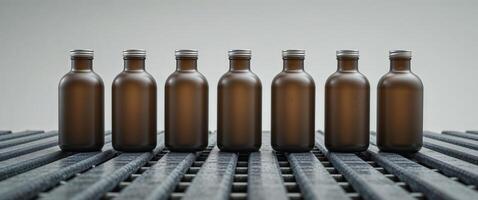 A row of brown bottles with silver lids on a conveyor belt photo