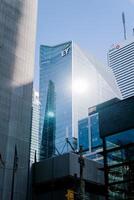 Toronto, Canada - 28 October 2023. Sunlight reflects off sleek glass skyscrapers with company logos EY and BMO prominently displayed. The modern structures tower amidst urban construction photo