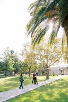 Girl-photographer walks along the path in the park to parents with a child photo