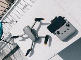 A modern drone alongside its controller resting on a table surface photo