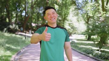 Athletic smiling runner fit man, happy about marathon achievement showing thumb up like gesture video