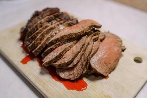 Thin slices of roast beef with blood lie on a wooden cutting board on the table photo