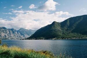 View from the shore to the sea against the backdrop of a forested mountain range photo
