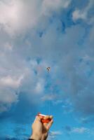 Man holds in his hand a spool of colorful kite string soaring in the sky photo