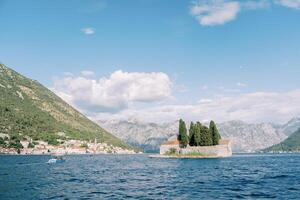 Island of St. George in the Bay of Kotor against the background of the coast of Perast at the foot of the mountains. Montenegro photo
