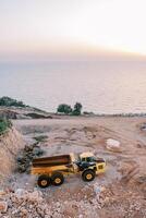 Loader stands in a quarry on the seashore at sunset. Top view photo