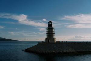 Lighthouse on a breakwater in the sea against the background of a twilight sky photo