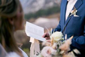 Groom reads the oath to the bride from a piece of paper photo