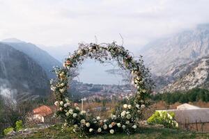 Round wedding arch stands on a mountain above the Bay of Kotor surrounded by a ridge in the fog photo