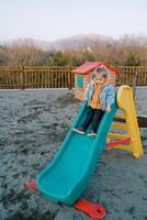 Little girl slides down the slide at the playground photo