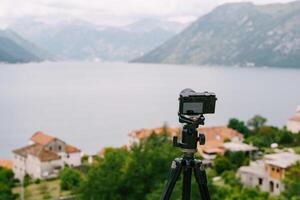 Camera on Tripod with Scenic View of Mountains and Water photo