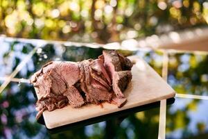 Thin slices of roast beef with blood lie on a wooden cutting board on a mirrored table on the balcony photo