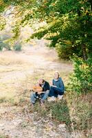 Mom squatted down next to dad sitting with a little boy in his arms photo