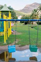 Plastic chain swings in the playground hanging over puddles after rain photo