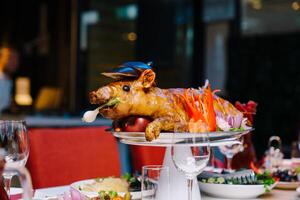 Roasted pig garnished with vegetables lies on a dish on a table in a restaurant photo