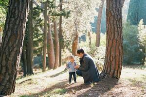 Mom squatted down in front of a little girl on a path in the forest photo