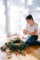 Smiling decorator paints a cone for a New Year wreath with a brush photo