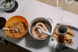 Bowl of minced meat stands near an electric meat grinder making sausage in the kitchen photo