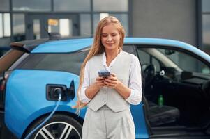 Process of charging, waiting. Woman ,on ,the electric cars station at daytime photo
