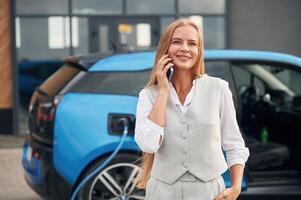 Process, of charging, waiting.. Woman on the electric cars station at daytime photo