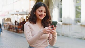 Indian woman use smartphone recommends social networks game application, showing pointing on phone video