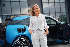 Standing, and ,posing. Woman on the ,electric cars charge station at daytime photo