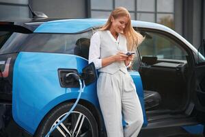 Standing and, waiting,. Woman on the electric cars charge station at daytime photo