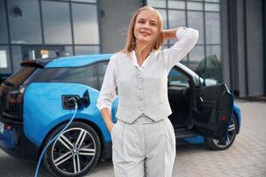 Standing ,,and posing. Woman on the electric cars charge station at daytime photo