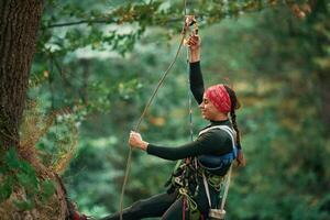 Woman is doing climbing in the forest by the use of safety equipment photo