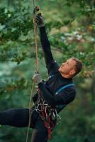 Man is doing climbing in the forest by use of safety equipment photo