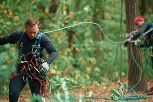 Preparing ,the, ropes. Man and woman doing climbing in forest with use of safety equipment photo