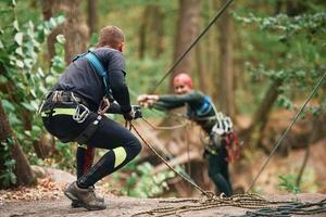 Preparing ,the ropes... Man and woman, doing climbing in forest with use of safety equipment photo