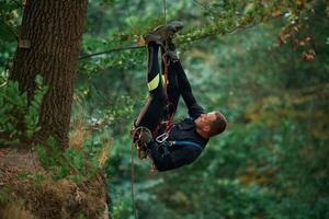 Hanging on a rope. Man is doing ,climbing, in the forest by use of safety equipment photo