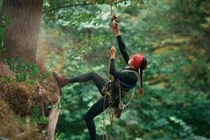 View from, the, side, hanging ,on, the rope. Woman is doing climbing in the forest by the use of safety equipment photo